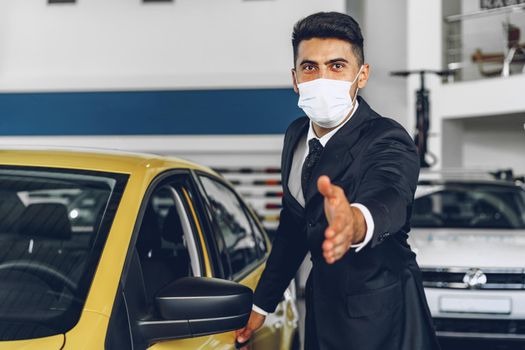 Man car dealer wearing protective medical mask on his working place