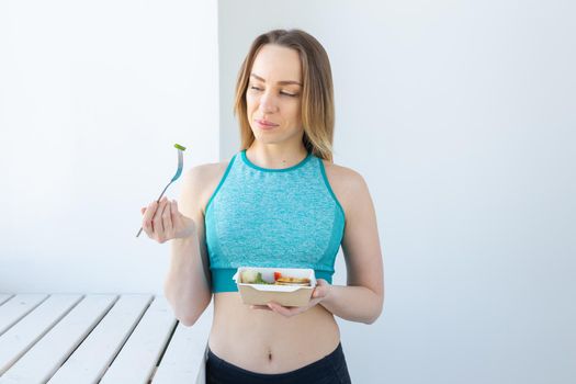 healthy eating, dieting and fitness concept - young woman eating vegetable and meat after workout
