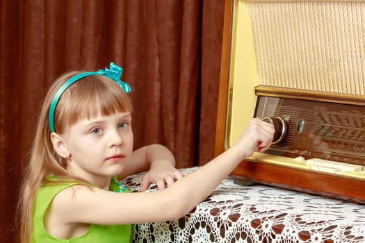 The girl turns the volume knob on the old radio. Retro style.