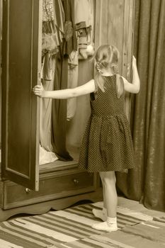 The little girl looks in the wardrobe.