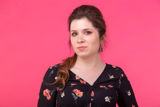 Portrait of a charming brown-eyed young positive woman in posing on a bright pink background