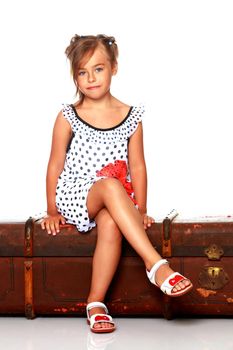 A little girl is sitting on a wooden box.