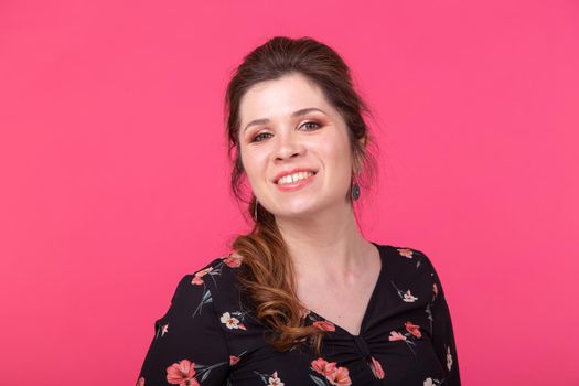 Close-up portrait of a charming brown-eyed young positive woman in posing on a bright pink background
