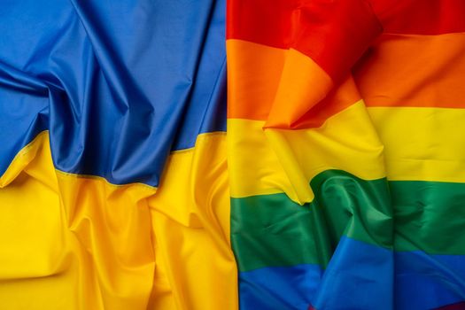 Flags of Ukraine and gay pride flag folded together