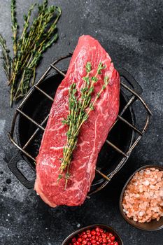 Raw Striploin steak on a grill, marbled beef. Black background. Top view