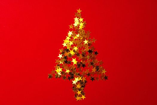 Christmas tree made of gold confetti on red background