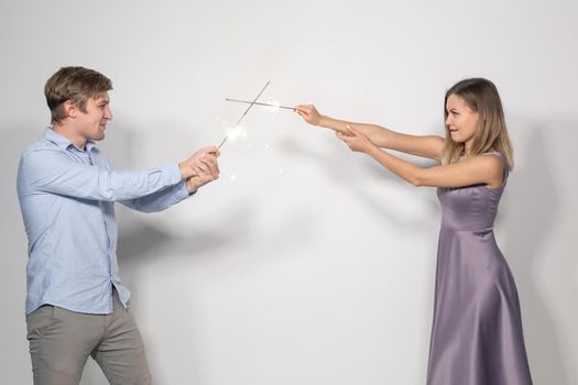 Celebration, party and holiday concept - Portrait of young couple fooling around with sparklers