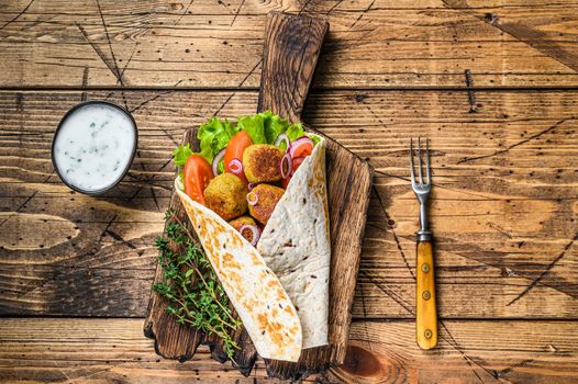 Vegetarian Tortilla wrap with falafel and fresh salad, vegan tacos. wooden background. Top view