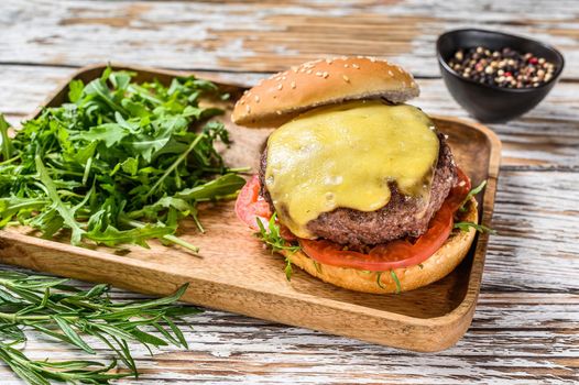 Big cheeseburger with beef, tomato, cheese and arugula. wooden background. Top view