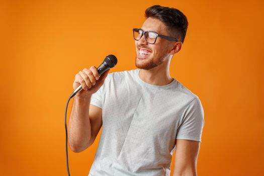 Hispanic young handsome man singing with joy in microphone