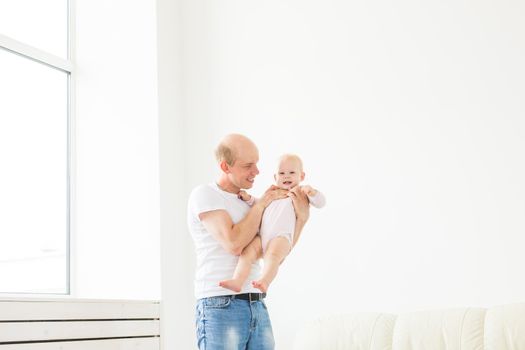 family, parenthood and fatherhood concept - happy father playing with little baby girl at home