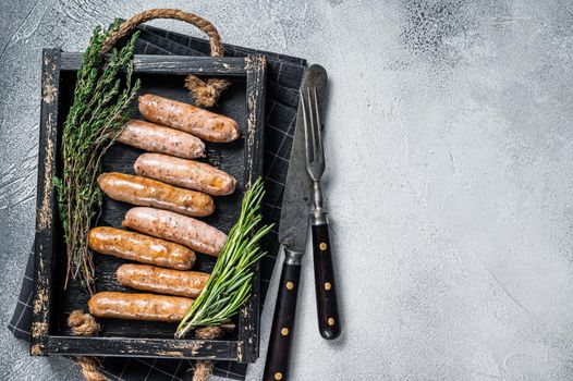 Roasted Bratwurst Hot Dog sausages in a wooden tray with herbs. White background. Top View. Copy space