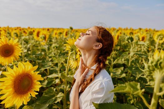 smiling woman with pigtails with closed eyes in sunflower field landscape summer. High quality photo