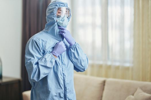 Man in mask, suit and glasses during disinfection in the room