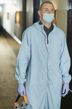 Man in protective suit going to disinfect hotel rooms