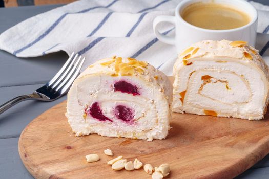 Biscuit roulade with cherry on wooden board