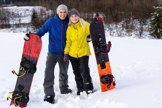 Portrait of happy couple of snowboarders outside during winter vacations