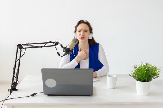 Radio host concept - Woman working as radio host sitting in front of microphone over white background in studio