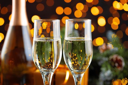 Champagne glass on blurred garland lights background
