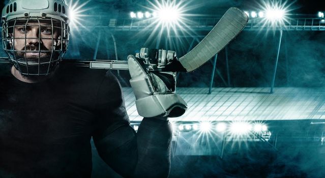 Ice Hockey player in the helmet and gloves on stadium with stick.