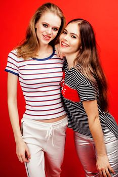 two best friends teenage girls together having fun, posing emotional on red background, besties happy smiling, lifestyle people concept close up