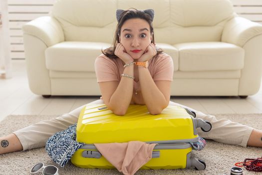 Holidays, voyage and travel concept - woman collects a yellow suitcase at home