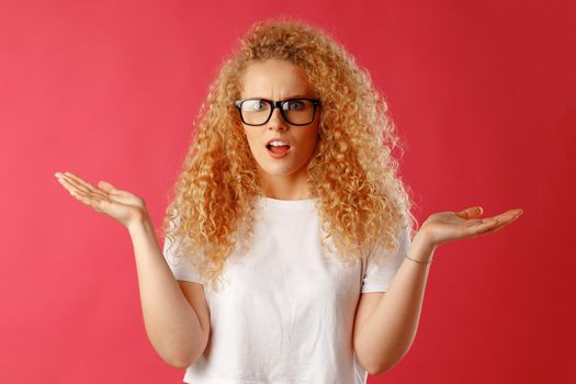 Shocked and amazed young curly woman in glasses