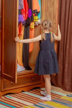 The little girl looks in the wardrobe.