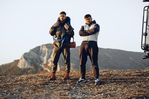 Two men hikers standing near off-road car getting ready to start their journey in mountains