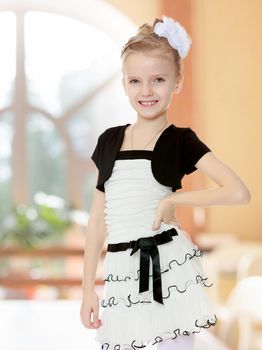 Beautiful little girl in a white short dress with a black belt.