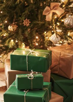 Christmas holiday delivery and sustainable gifts concept. Green gift boxes wrapped in eco-friendly packaging with recycled paper under decorated xmas tree