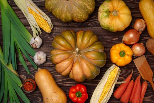 Variety of ripe vegetables including pumpkin and corn on dark background