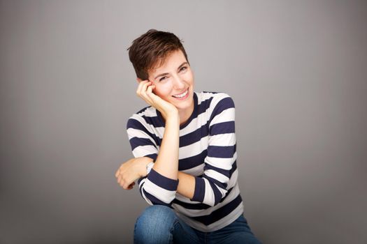 happy young woman with short hair against gray wall