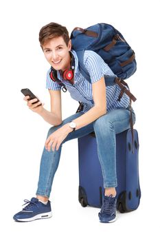 young woman sitting on suitcase with mobile phone in hand