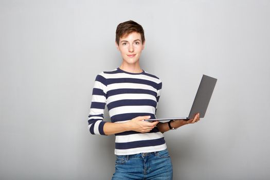 confident young woman with short hair holding laptop computer