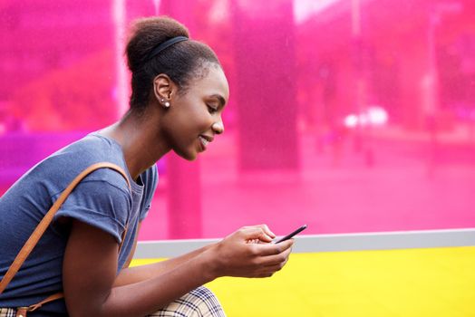 smiling african american woman looking at mobile phone
