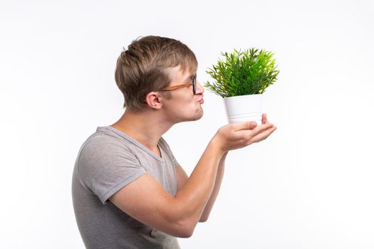 Nature, fun, fool around and nerd concept - Portrait of funny young man kissing a plant over the white background