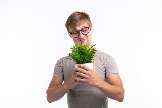 Nature, fun, fool around and nerd concept - Portrait of funny young man holding a plant over the white background
