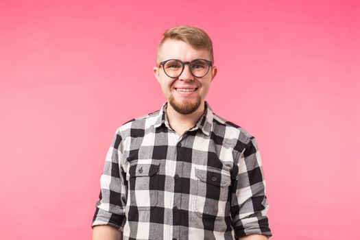 Student, geek and people concept - a young man in glasses smiling over the pink background