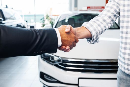 Customer shaking hands with professional car dealer at automobile dealership