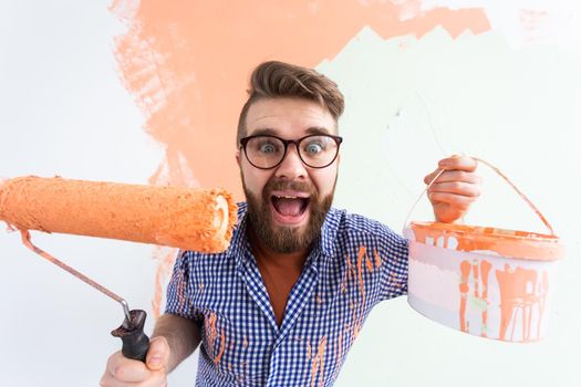 Funny man with painting roller indoors. Redecoration, renovation, apartment repair and refreshment concept.