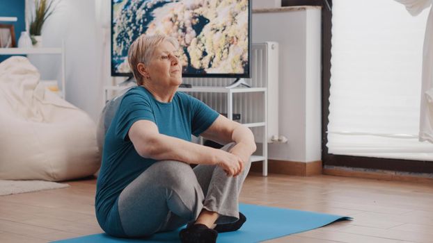 Pensioner sitting on yoga mat to meditate after training