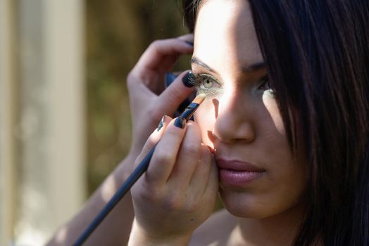 Make-up applying eyeshadow on model's eye
