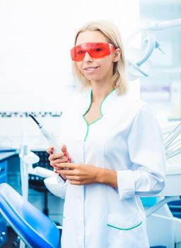 Dentist with ultraviolet lamp and special red glasses
