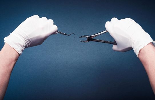 Hands in gloves holding surgery dental tools