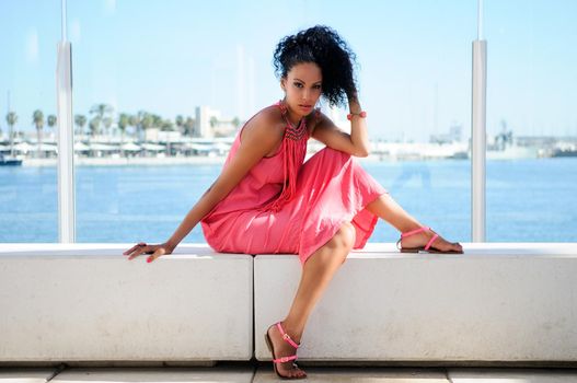 Black woman with pink dress and earrings. Afro hairstyle