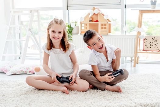 Little girl and boy playing on console