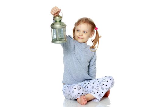 A little girl is holding a lamp.