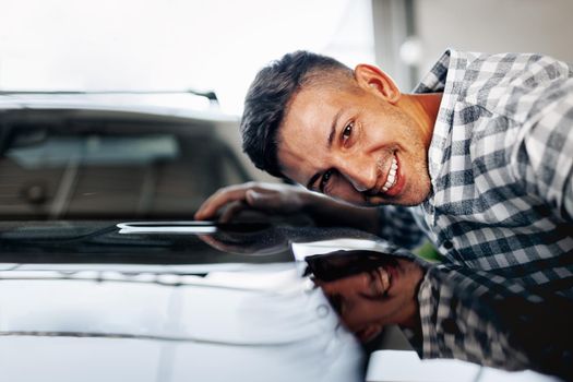 Cheerful young man customer buys a new car in a dealership