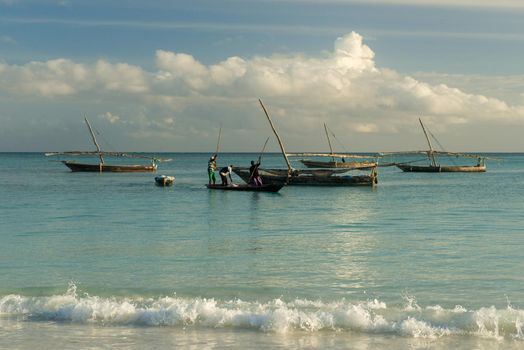 boats with fishermen in ocean near fishing village